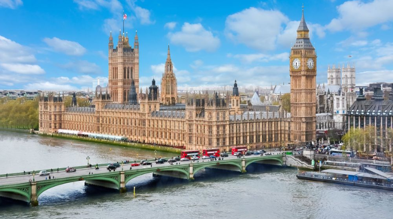 Big Ben and the Houses of Parliament along the River Thames, illuminated at night with a golden glow.