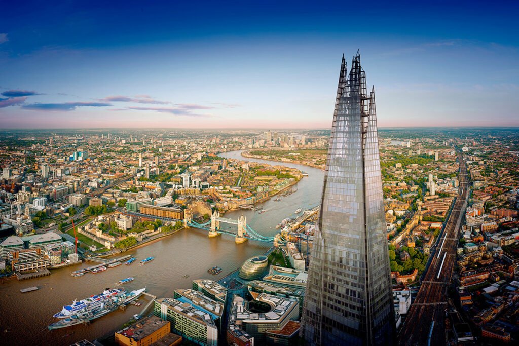 The Shard in London, a towering glass skyscraper with a stunning blue sky background.