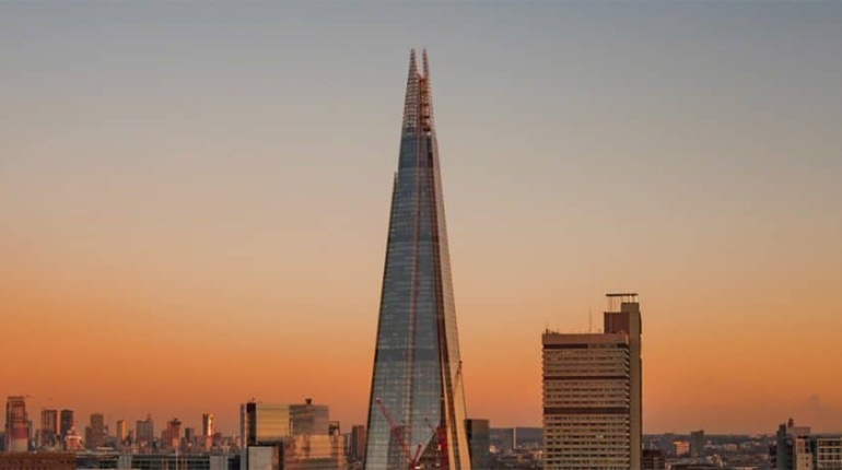 The Shard, a sleek glass skyscraper towering above London’s skyline with a sunset backdrop.