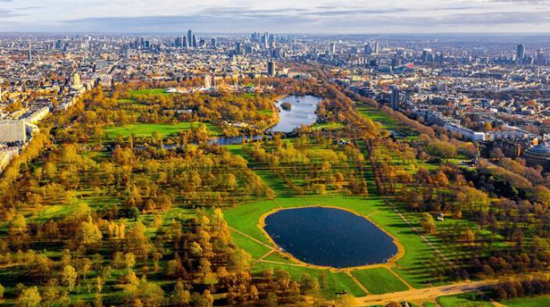 Hyde Park with its lush green lawns, a tranquil lake, and people enjoying the outdoors under a sunny sky.