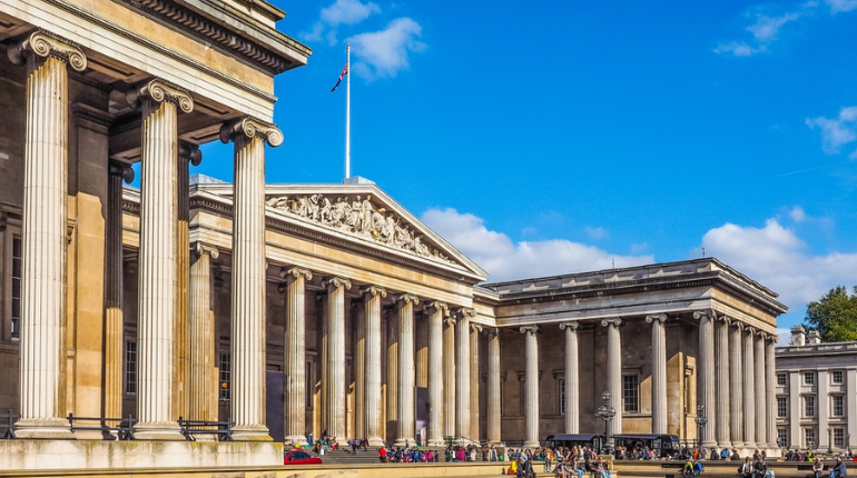 The grand facade of The British Museum in London, featuring its iconic Greek-style columns and a bustling courtyard.