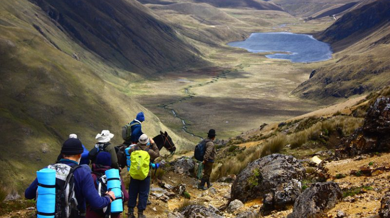 A hiker standing on a trail in Ecuador’s Andes, surrounded by breathtaking mountain views and lush landscapes, showcasing the beauty of hiking in Ecuador.